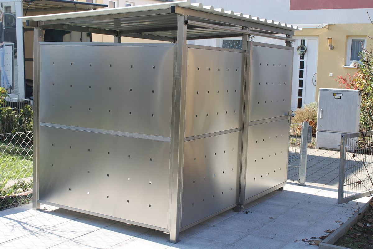 Mülltonnenbox in Edelstahl-Ausführung mit gelochten Metallpaneelen an einem Wohnhaus