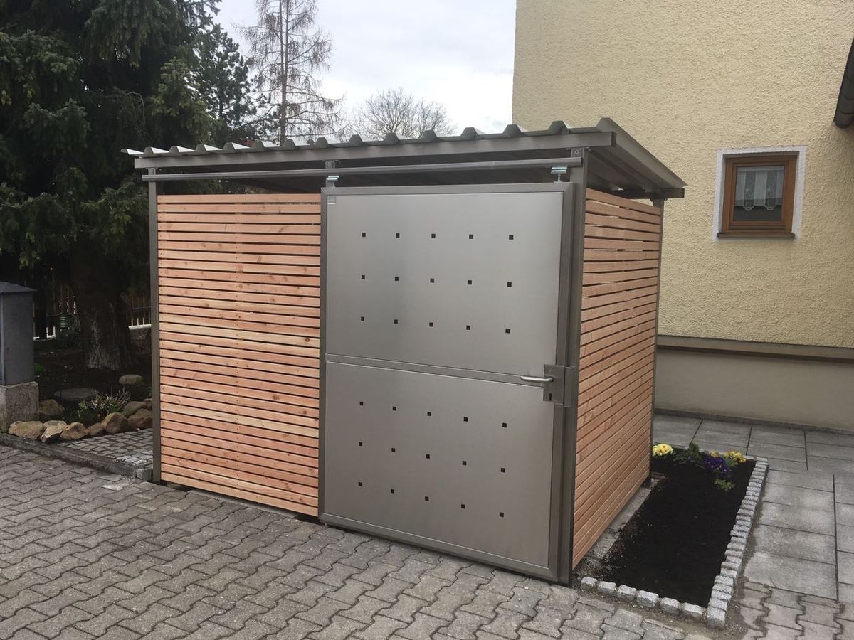 Kompaktes Mülltonnenhaus aus Lärchenholz mit Edelstahltür im Vorgarten eines Einfamilienhauses